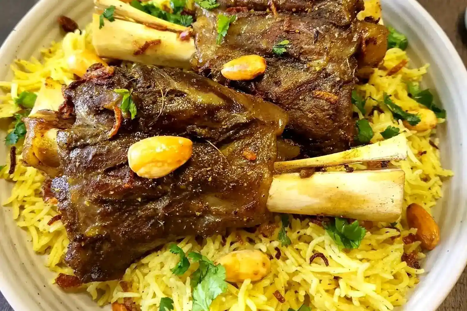Slow-cooked lamb shanks served over yellow mandi rice with almonds and herbs
